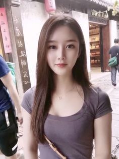 Woman with long hair wearing a gray t-shirt and necklace on a street