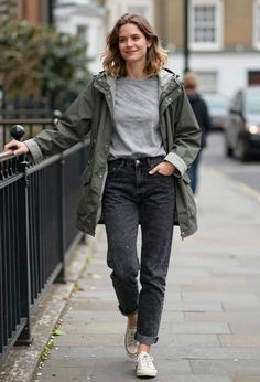 Woman in a khaki jacket and black jeans walking on a street
