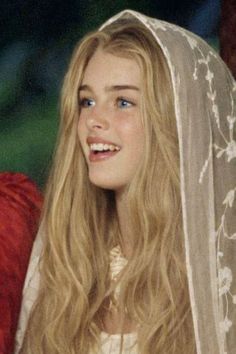 Young woman with long blonde hair and a lace veil smiling