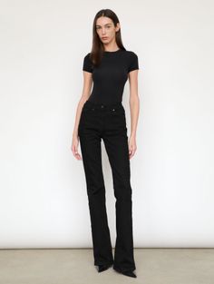 Woman with long hair wearing a black t-shirt and black jeans in a studio