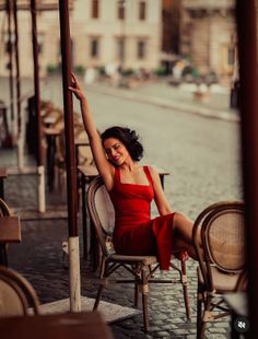 Woman in a red dress sitting at an outdoor cafe on a cobblestone street