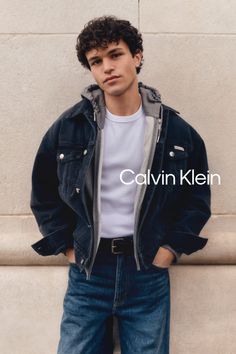 Man with curly hair wearing a denim jacket and jeans outdoors