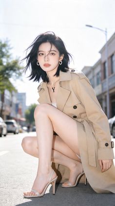 Woman in a trench coat and high heels crouching on a street