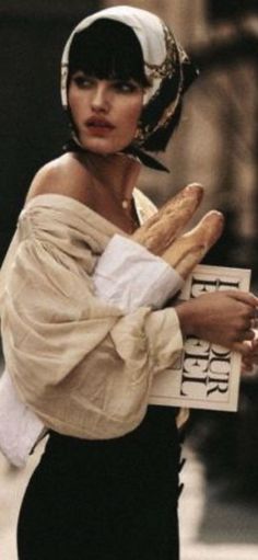 Woman with a head scarf and off-shoulder top holding baguettes