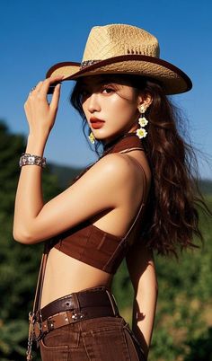 Woman in a cowboy hat and crop top posing outdoors under a clear sky