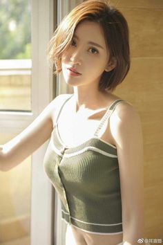 Woman with short hair in a green top by a window with soft lighting