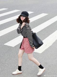 Woman in a striped shirt and pink shorts walking on a crosswalk