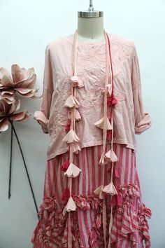 Pink top and striped ruffled skirt on a mannequin with fabric flower garland