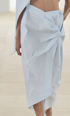 Close up of a person wearing light blue fabric with a knotted detail and exposed midriff