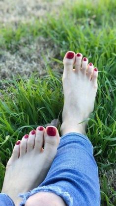 Bare feet with red nail polish resting on green grass