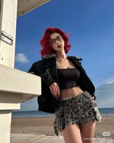 Woman with red hair in a crop top and furry skirt on a beach