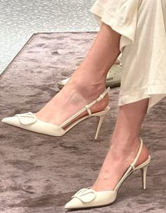 Person wearing white slingback high heels with pointed toes indoors