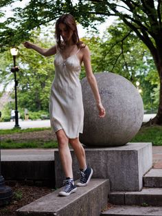 Woman in a white slip dress and sneakers walking in a park