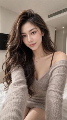 Woman with long hair wearing an off-shoulder sweater and heart necklace indoors