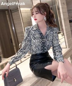 Woman in a snake print shirt and black leather skirt sitting indoors