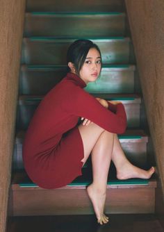 Woman in a red dress sitting on wooden stairs indoors