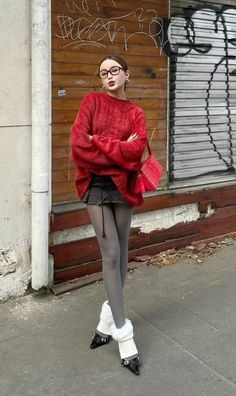 Woman in a red sweater, mini skirt, and leg warmers posing outdoors