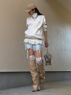 Woman in a white track jacket, lace skirt, and knee high boots