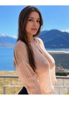 Woman in a sheer knitted top outdoors with mountains and a lake in the background