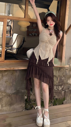 Woman in a beige top and brown ruffle skirt with espadrille shoes outdoors