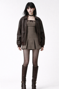 Woman in a brown leather jacket and plaid dress with knee high boots