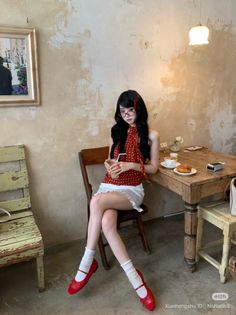Woman with long black hair in a red polka dot top and white mini skirt sitting in a cafe