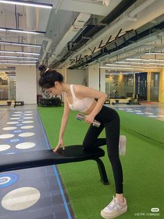 Woman in a sports bra and leggings exercising with a dumbbell in a gym