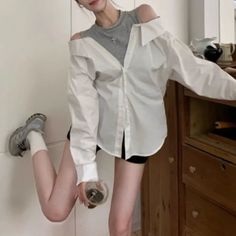 Woman in an off-shoulder white shirt and black shorts holding a drink