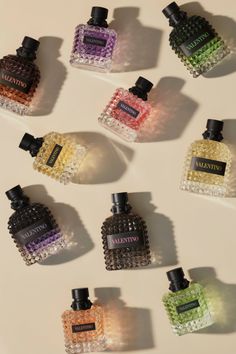 Multiple colorful perfume bottles with textured glass on a beige background