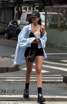 Woman in a black cap and light blue shirt walking on a street