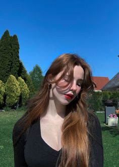 Woman with long hair and red lipstick in a black top outdoors on a sunny day
