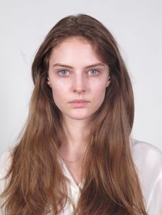 Woman with long brown hair and blue eyes wearing a white shirt