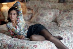 Woman in a patterned shirt and mini skirt lying on a bed