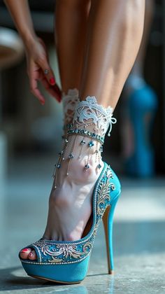 Close up of a foot in a teal high heel with an ornate lace and jewel anklet