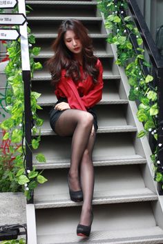 Woman in a red shirt and black skirt sitting on outdoor stairs