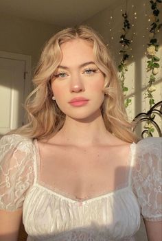 Blonde woman in a white lace top with soft lighting indoors