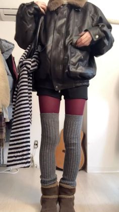 Person in a leather jacket, burgundy tights, and leg warmers indoors
