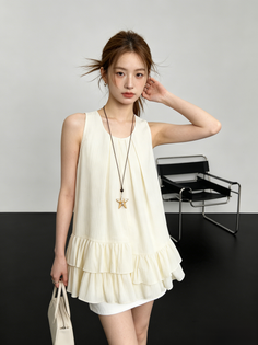 Woman in a cream sleeveless top with a starfish necklace in a studio
