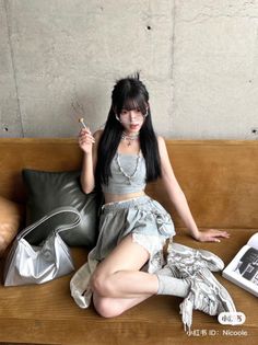 Woman with long black hair wearing a crop top and mini skirt, sitting on a couch
