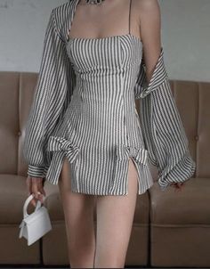 Woman in a striped mini dress with a matching jacket and a white handbag