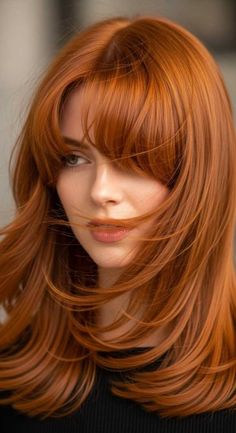 Woman with long, layered red hair and bangs looking to the side