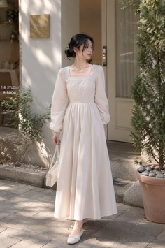 Woman in a long white dress standing outdoors in soft daylight