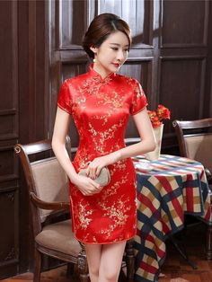 Woman in a red cheongsam with gold floral patterns holding a clutch bag