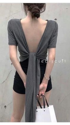 Woman in an open back top and black shorts holding a shopping bag