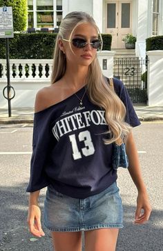 Woman with blonde hair and sunglasses wearing an off-shoulder top and denim skirt