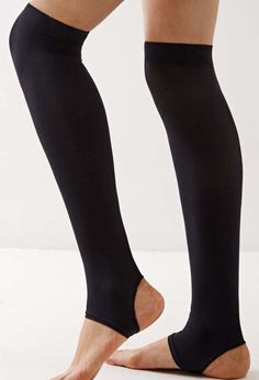 Person wearing black stirrup leggings with bare feet on a white background
