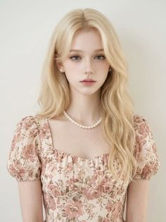 Woman with blonde hair wearing a floral dress and pearl necklace