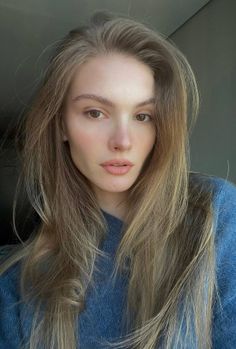 Woman with long blonde hair wearing a blue sweater, captured in soft lighting