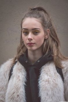 Woman with yellow eyeshadow and a fur coat over a black hoodie