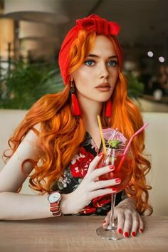 Woman with red hair and a red turban holding a cocktail